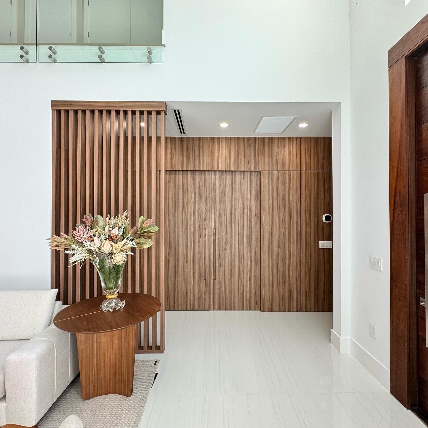 Entry with walnut slat divider and paneled wall