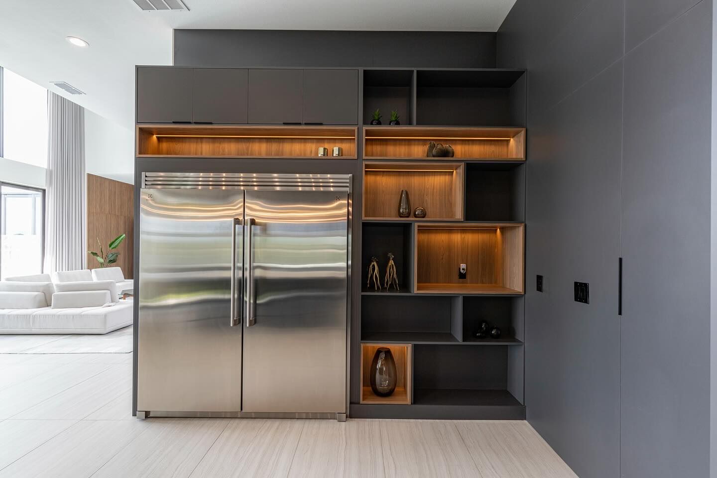 Cabinet wall around a stainless refrigerator with lit shelves