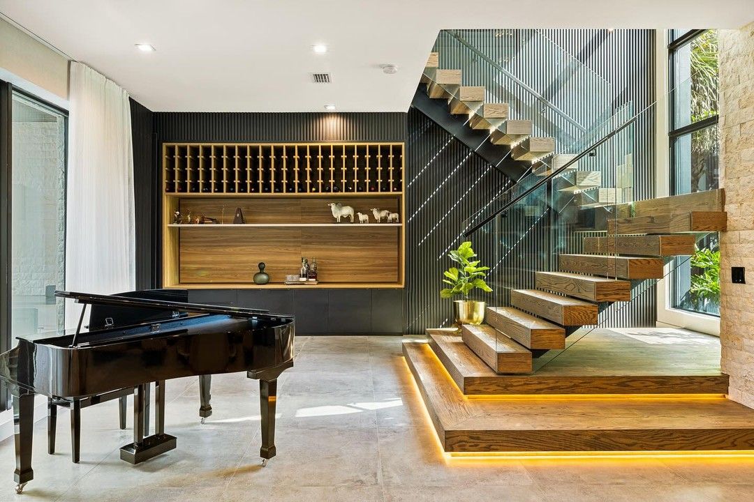 Grand piano beside a floating wood staircase with a built-in wine shelf